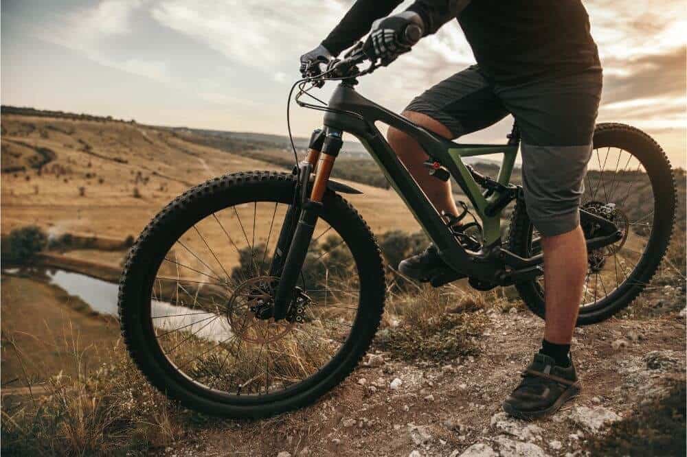 Man standing with a bike on a hill