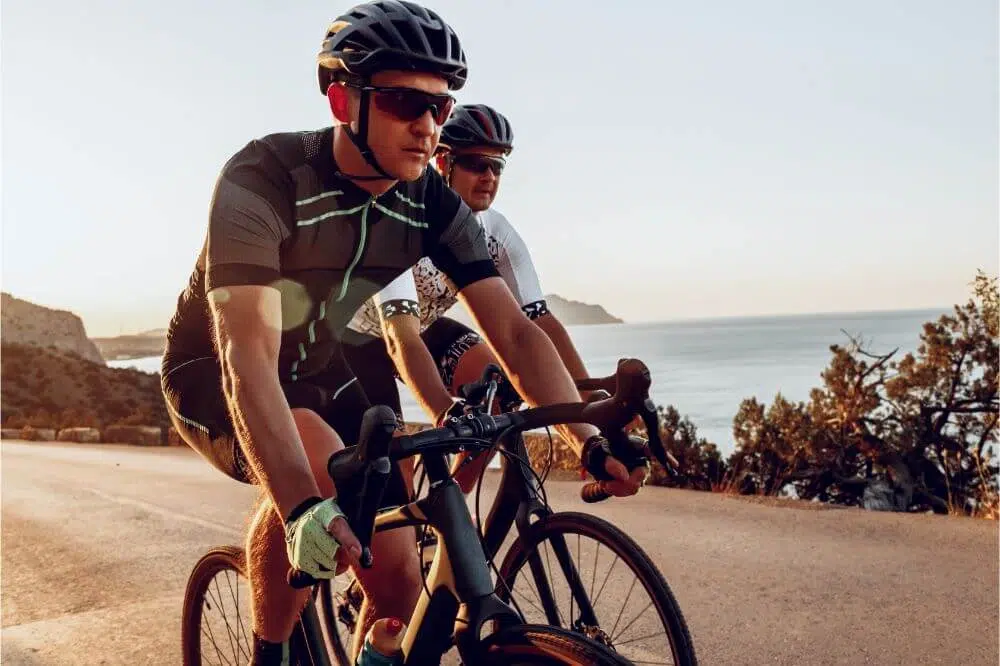 two main riding a bike near the sea